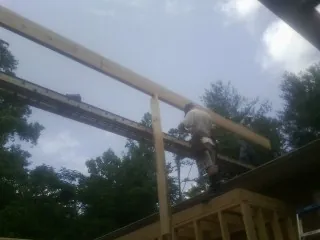 Carpenter setting a ridge beam over a new addition frame — Ice Dam Removal by Roofing Brothers in Altair