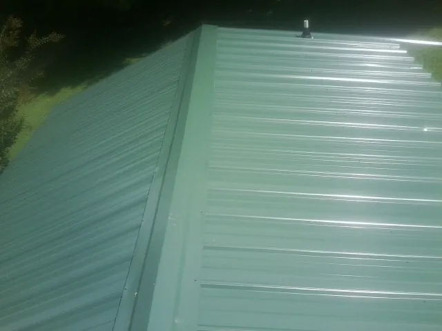 New green metal panels meeting at the ridge of a roof — Flat Roof Repair work by our crew in Altair