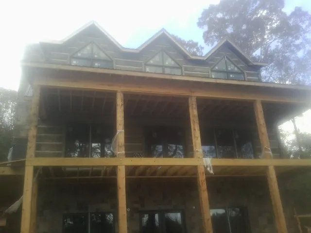 Dormers and porch framing on a large log home under construction — Roof Coating work by our crew in Altair