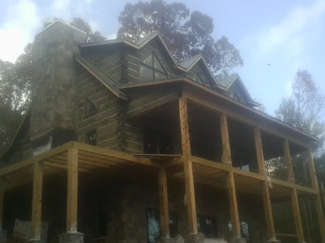 Stone chimney and dormers on a large log home with a timber porch in Altair