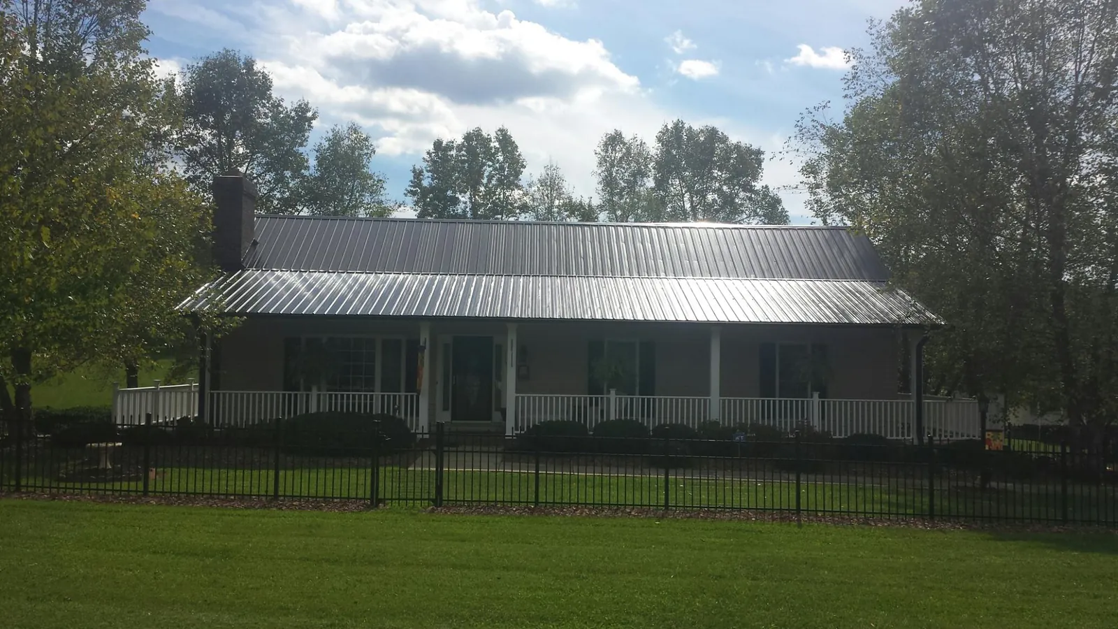 Gray metal roof on a brick ranch with a full width front porch — Gutter Guard Installation work by our crew in Altair
