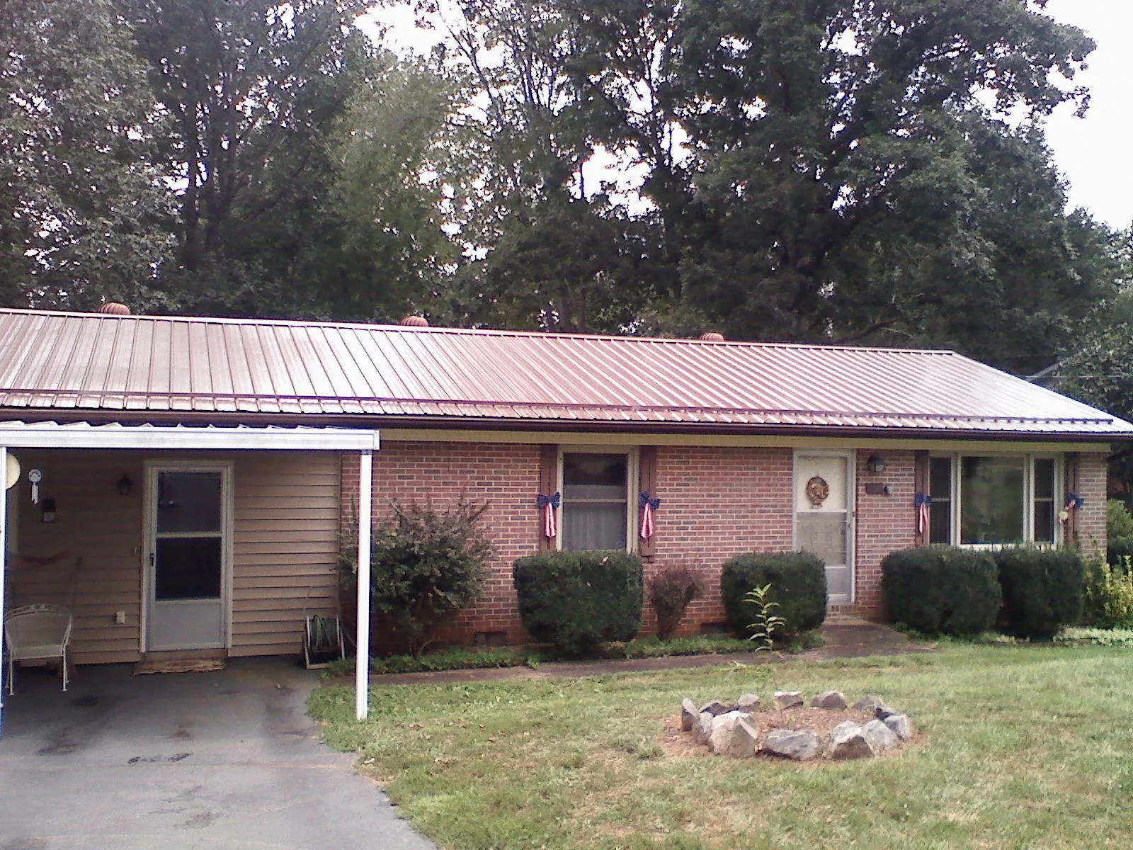 Bronze metal roof and carport on a brick ranch home — Roof Repair work by our crew in Altair