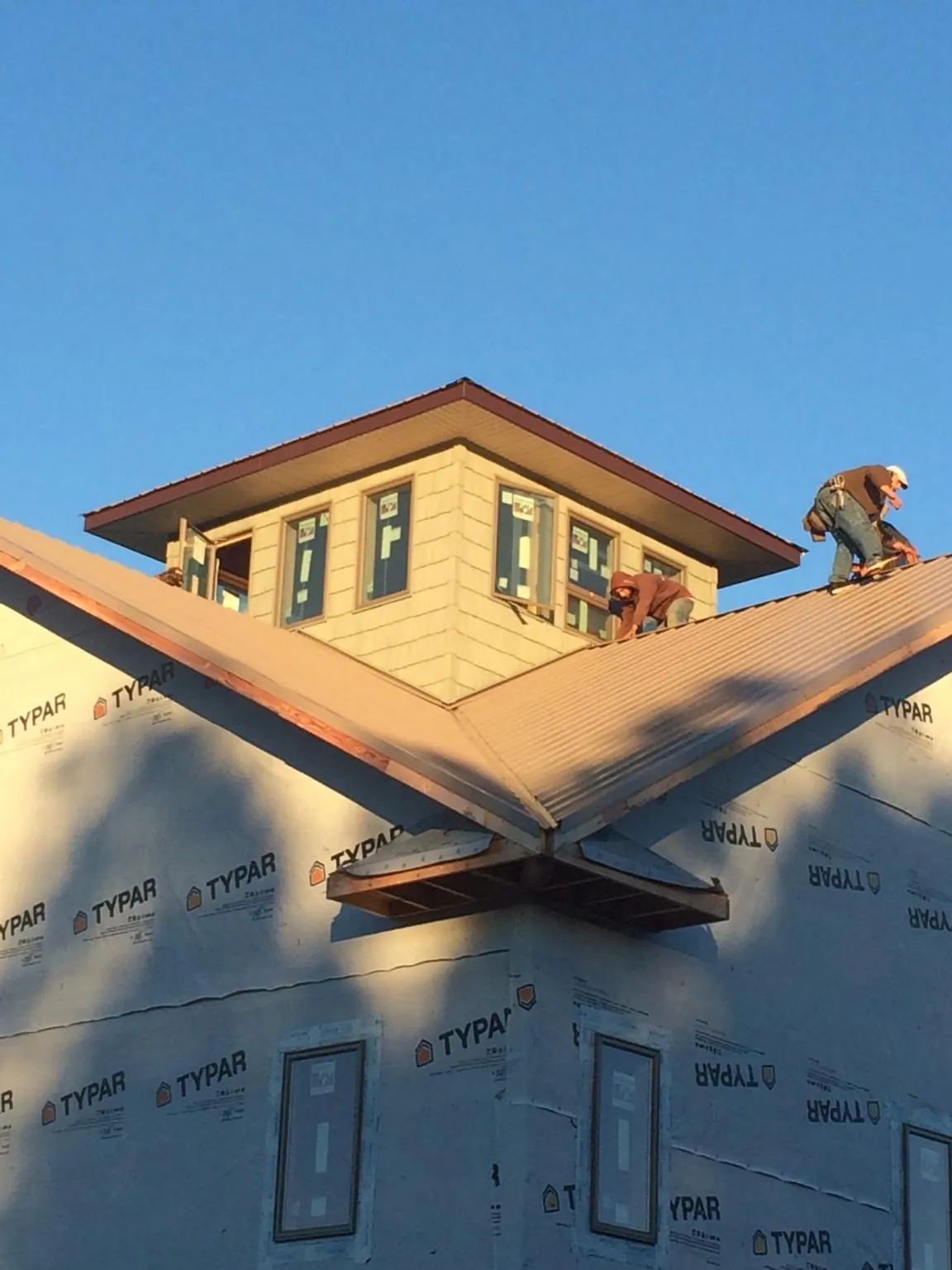 Roofers working around a rooftop cupola on a new metal roof at sunset — Roof Waterproofing in Altair by Roofing Brothers